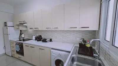 a white kitchen with a washing machine and a sink at STAY Amphora Apartment in Larnaka