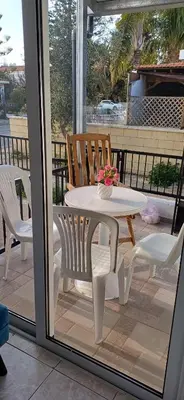 a white table and chairs on a porch with a table and flowers at Magic Maisonette 250m from the beach in Larnaka