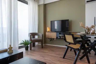 a living room with a television and a table and chairs at Luna - Homely Studio W Balcony in Larnaca in Larnaka
