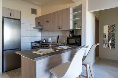 a kitchen with a counter with two white chairs at Mosaic - 1 Bedroom Apartment in Larnaca in Larnaka
