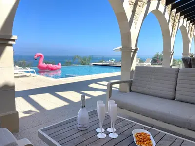 a table with wine bottles and a tray of food next to a pool at Sunrise Dream Villa-Protaras in Protaras