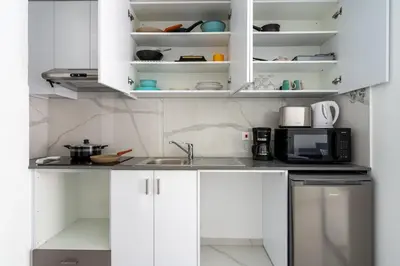 a kitchen with white cabinets and a microwave at Sunny Side Studio W Terrace in Larnaca in Larnaka