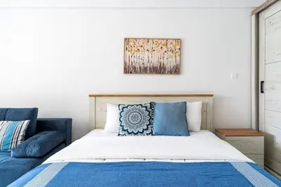 a bedroom with a bed and a blue couch at Sunny Side Studio W Terrace in Larnaca in Larnaka