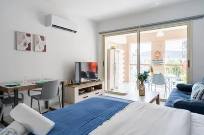 a bedroom with a blue bed and a living room at Sunny Side Studio W Terrace in Larnaca in Larnaka