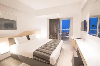 a hotel room with a large bed and a balcony at Evalena Beach Hotel in Protaras