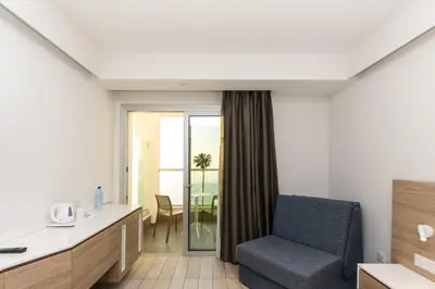 a hotel room with a chair and a balcony at Evalena Beach Hotel in Protaras
