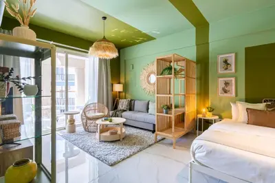 a bedroom with green walls and a bed and a couch at Sunstone - Cozy Studio W Terrace in Larnaca in Larnaka