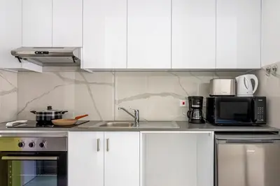 a kitchen with white cabinets and a sink and a microwave at Sunstone - Cozy Studio W Terrace in Larnaca in Larnaka