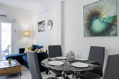a dining room with a table and a blue couch at Vibe - 1 Bedroom Apartment W Balcony in Larnaca in Larnaka