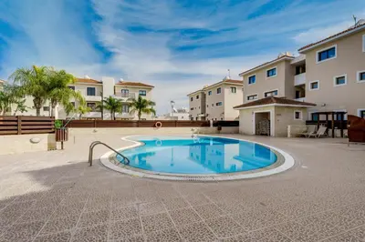 a swimming pool in the middle of a courtyard with buildings at Apartment Sun 'n Joy in Paralimni