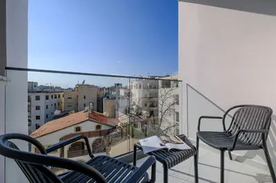 a balcony with two chairs and a view of a city at Maestro City Apartments in Larnaka