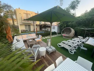 a patio with a bunch of chairs and an umbrella at Sunshine Villa Private Pool Luxury Garden 2' walk to Kalamies beach Pernera in Protaras