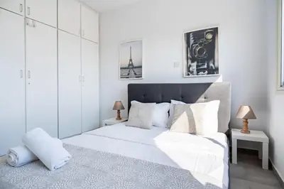a white bedroom with a large bed and two lamps at Liric - 3 Bedroom Apt W Balcony in Larnaca in Larnaka
