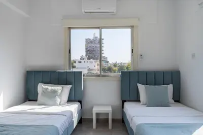 two beds in a room with a window at Liric - 3 Bedroom Apt W Balcony in Larnaca in Larnaka