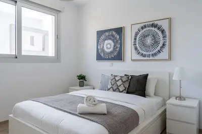 a white bedroom with a large white bed and a window at Valleria - 2 BR Apartment W Pool in Larnaca in Larnaka