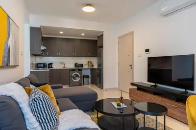 a living room with a couch and a tv at Valleria - 2 BR Apartment W Pool in Larnaca in Larnaka