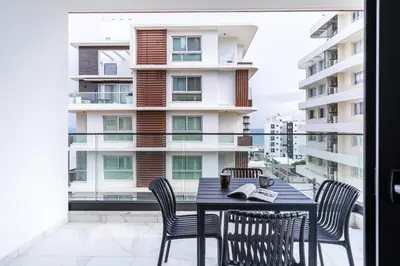 a table and chairs on a balcony with a building at Dusk - Harmonic Studio by Plus 49 in Mackenzie in Larnaka