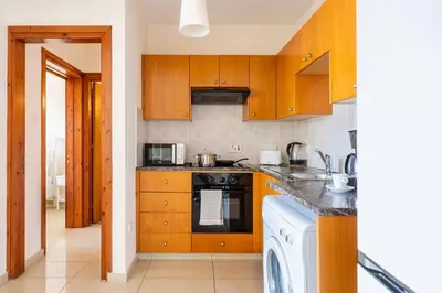 a kitchen with wooden cabinets and a dishwasher at Glade - 1 Bedroom Apt W Balcony in Larnaca in Larnaka
