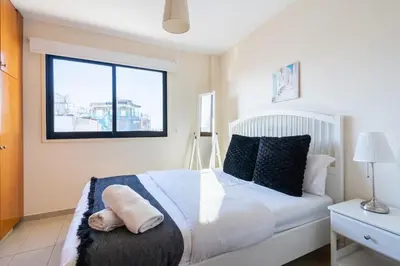 a bedroom with a white bed with a window at Glade - 1 Bedroom Apt W Balcony in Larnaca in Larnaka
