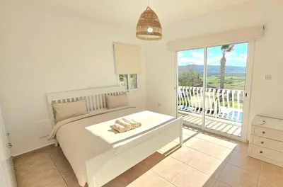 a white bedroom with a bed and a balcony at White Cove Villa, Limassol in Pyrgos