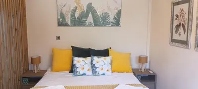 a bedroom with a bed with yellow and blue pillows at Plumeria Place Bright and spacious studio in Larnaka