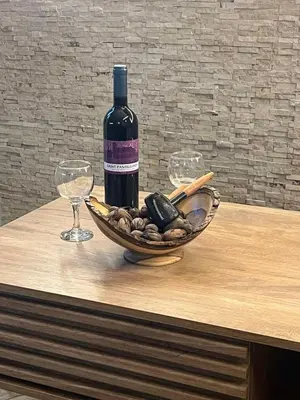 a bottle of wine and a bowl of nuts and a wine glass at Plumeria Place Bright and spacious studio in Larnaka