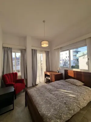 a bedroom with a bed and a desk and windows at Jacobs home in Larnaka