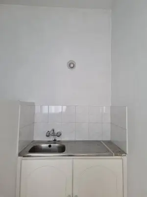 a kitchen with a sink and a white tiled wall at Jacobs home in Larnaka