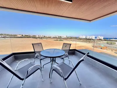 a table and chairs on a balcony with a view at Mackenzie Seaside Apartment in Larnaka