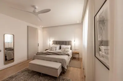 a white bedroom with a bed and a ceiling fan at Elysium Heights in Nicosia