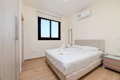 a white bedroom with a bed and a window at Quattro Rise in Paralimni