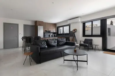 a living room with a black couch and a kitchen at Urban Condo 33 with Balcony - 2 Bdr in Nicosia