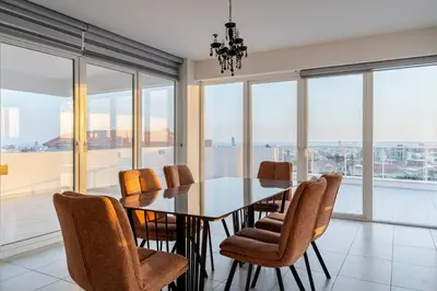 a dining room with a table and chairs and windows at Penthouse Great View Hydromassage Penthouse hottub in Limassol