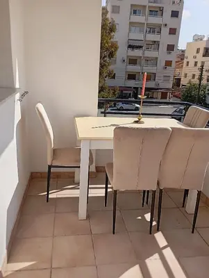 a table and chairs on a balcony with a view of a building at Eat well Sleep Well in Larnaka