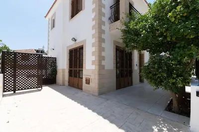 a large white building with wooden doors and a fence at Malama 28 Villa Ekaterina in Paralimni
