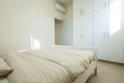 a white bedroom with a large bed with white cabinets at Lito - Slow Living in Larnaka