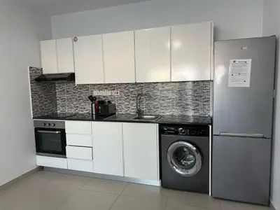 a kitchen with white cabinets and a washing machine at Dene Hollow Ayia Napa 2 in Ayia Napa