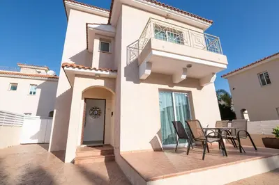 a house with a balcony and a table and chairs at Pernera Gardens Villa Ekaterina in Protaras
