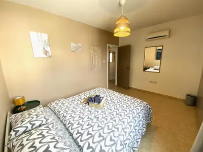 a bedroom with a bed with a white and black comforter at 2Br Apt - 5mins walk to the Beach with Internet access in Larnaka