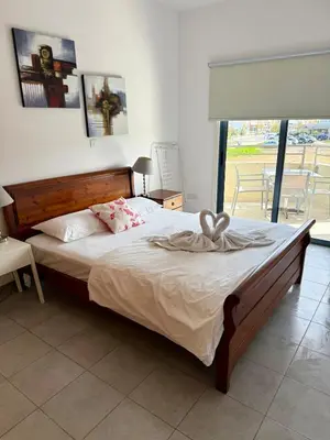 a bedroom with a large bed with a wooden headboard at Elena One Bedroom Budget Apt - License no 06991 in Paralimni