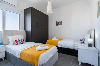 a bedroom with two beds and a large window at Olympus 2-Bedroom Apartment in Larnaka