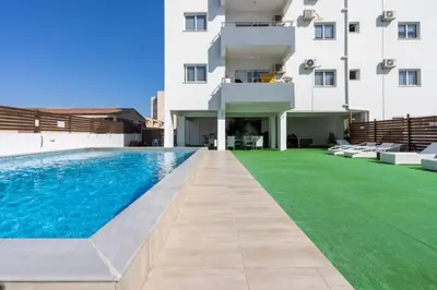 a swimming pool in front of a building at Olympus 2-Bedroom Apartment in Larnaka