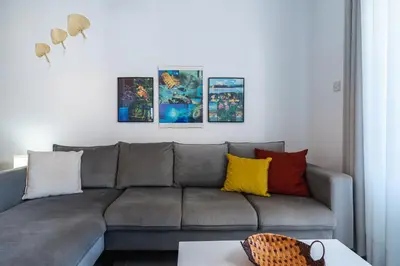 a living room with a gray couch with colorful pillows at Olympus 2-Bedroom Apartment in Larnaka