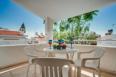 a table and chairs on a balcony with wine glasses at Villa Andreas in Protaras