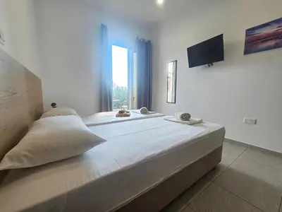 a bedroom with a large bed with a tv on the wall at Piazza Napa Studio Apts self serviced in Ayia Napa