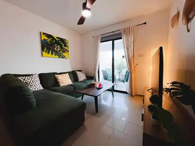 a living room with a green couch and a table at Déjà Blue Apartment Kyklades BC7 - workspace, pool, gym, nearby beach in Protaras