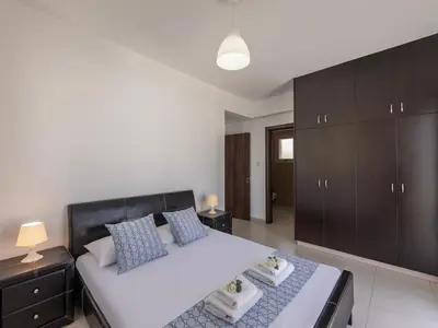 a bedroom with a large white bed and brown cabinets at villa Sama palms 21 in Protaras