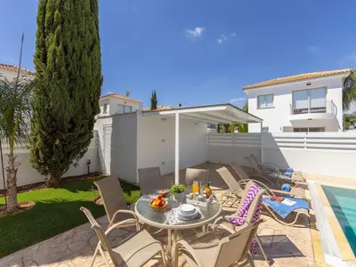 a patio with a table and chairs next to a pool at villa Sama palms 21 in Protaras