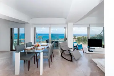 a dining room with a table and chairs and the ocean at Apartment Marisol - Beachfront in Protaras
