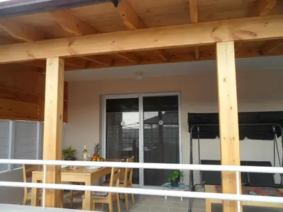 a porch with wooden beams and a table and chairs at Nissi Area,Ground Floor Flat, Free internet in Ayia Napa